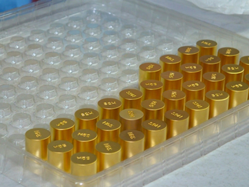 Golden perfume bottle caps neatly arranged in a protective blister tray for safe packaging