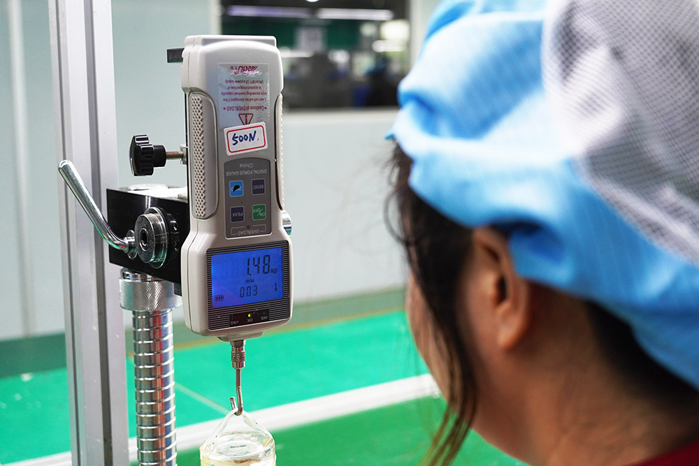 Quality technician conducting a digital pull-force test on a custom Zamak perfume cap to ensure proper fitment.